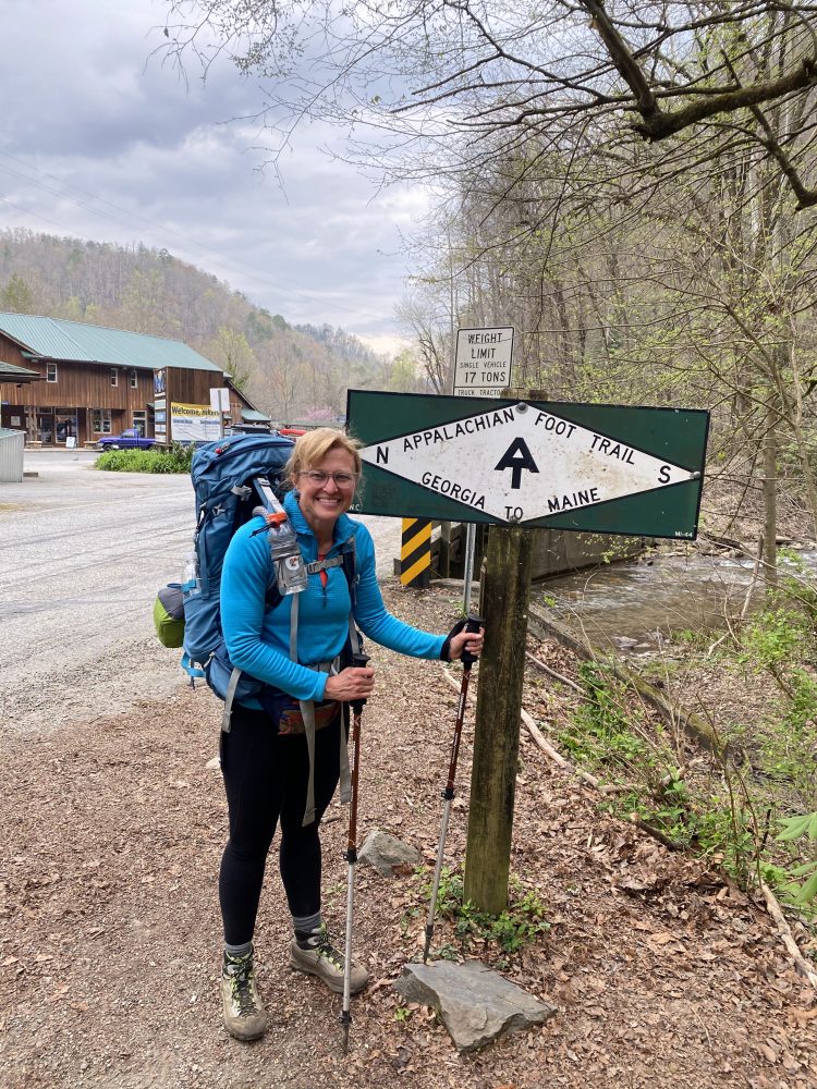 woman with backpack in front of sign post for Appalachian Trail