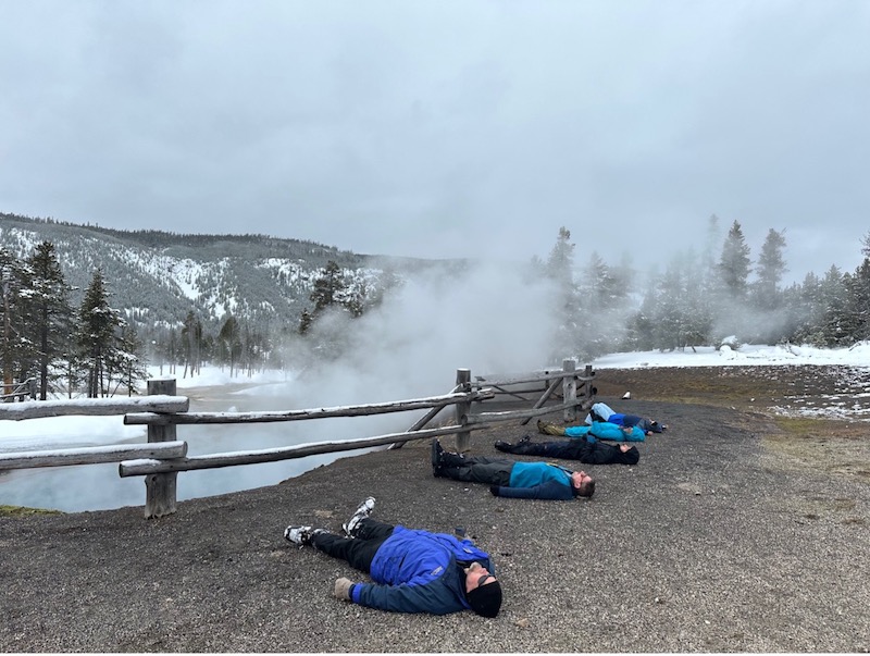 people laying on the ground near a hot spring